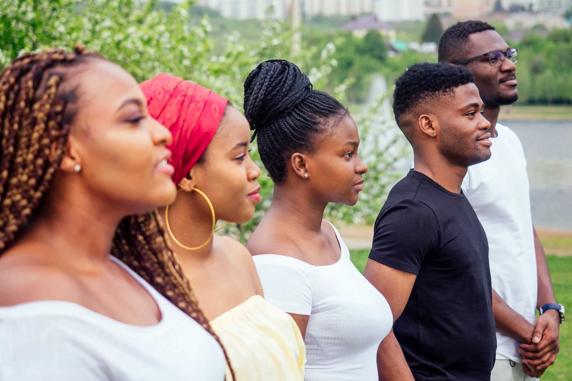group of five smiling african-american men and women walking outside cloudy weather